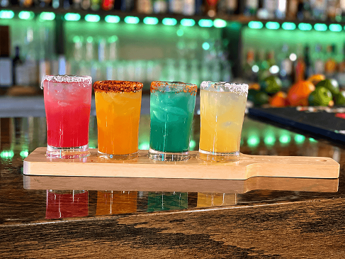 Flight of four margaritas in different flavors, served together with zesty seasoned rims